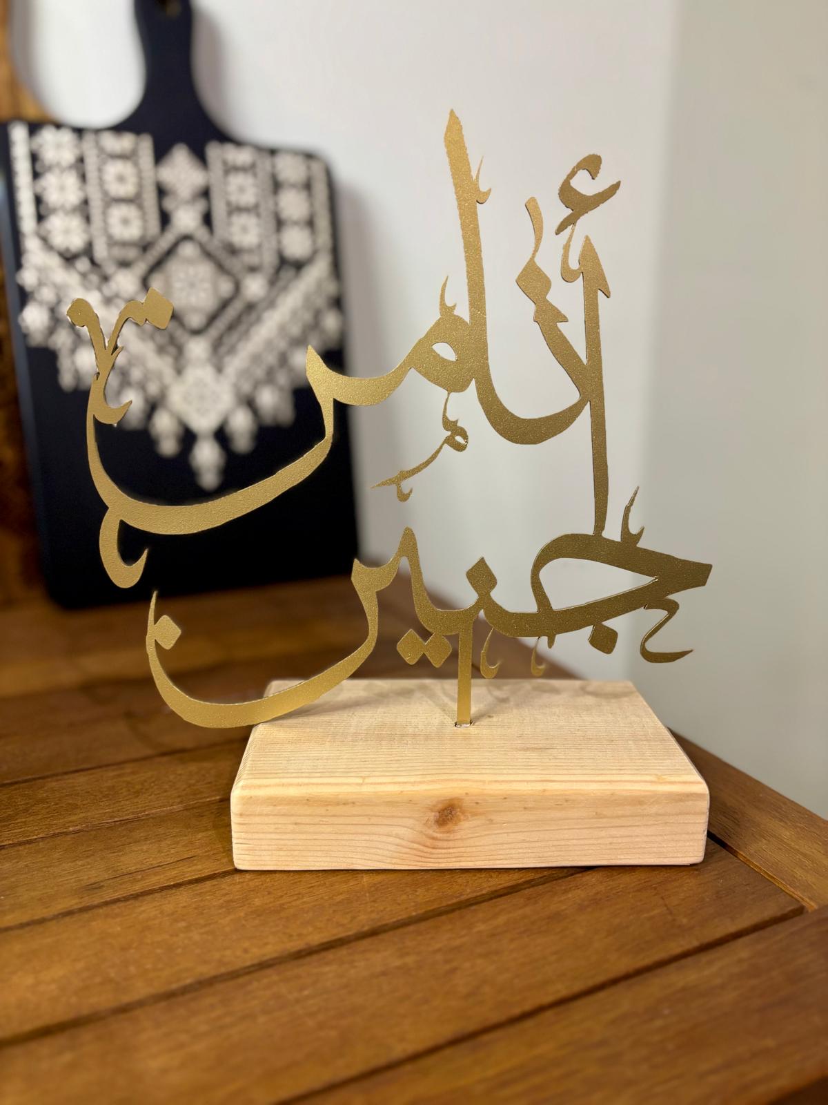 "Ana min Janin" Gold Insignia on Natural Wood Base.